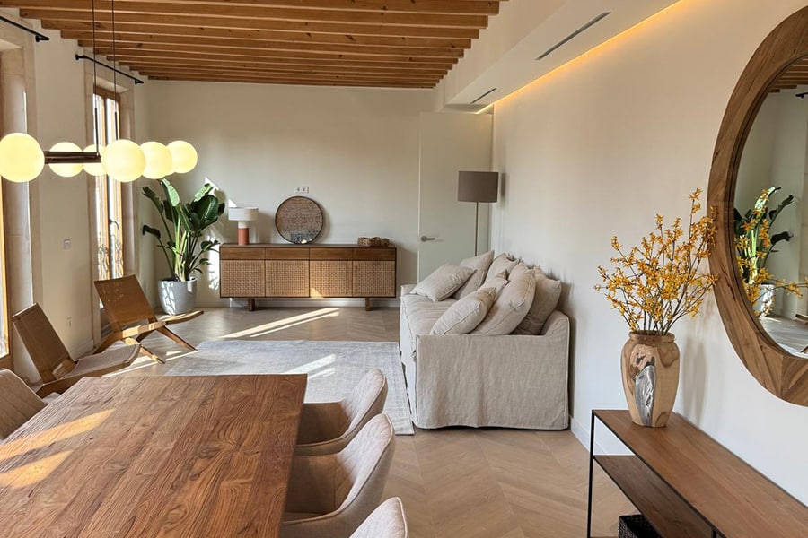 Salón comedor en vivienda rehabilitada en casco antiguo de Palma con vigas de madera y acabados naturales